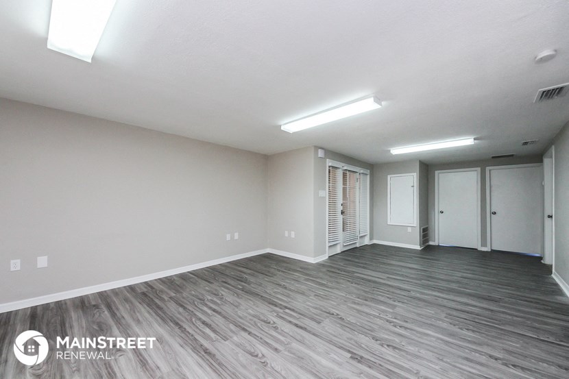 an empty living room with wood flooring and white walls