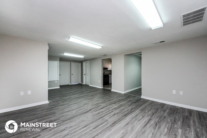 an empty living room with wood flooring and white walls