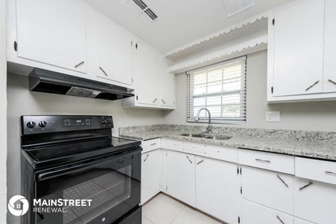a kitchen with white cabinets and black appliances and white counter tops