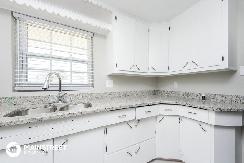a white kitchen with white cabinets and granite counter tops