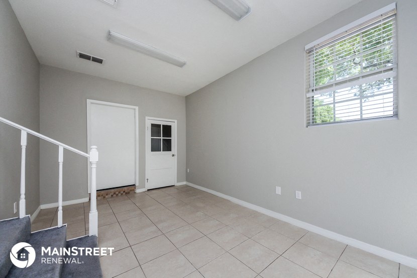 an empty living room with a white door and a window