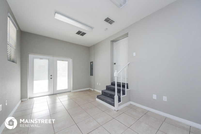 an empty living room with a staircase and a white door