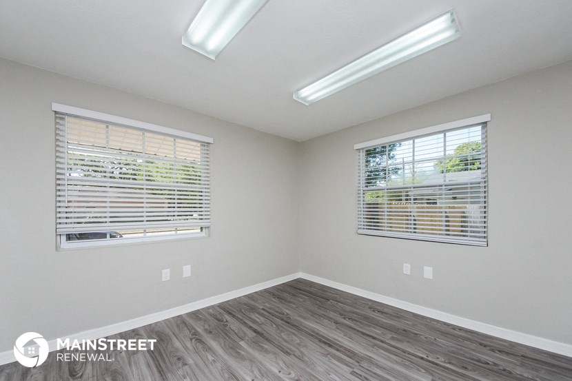 the spacious living room with two windows and wood flooring