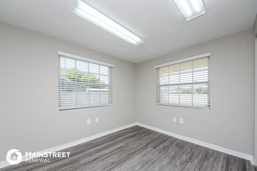 the living room of a new home with wood flooring and two windows