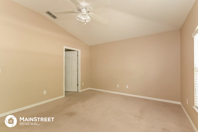 the spacious living room with carpeting and a ceiling fan