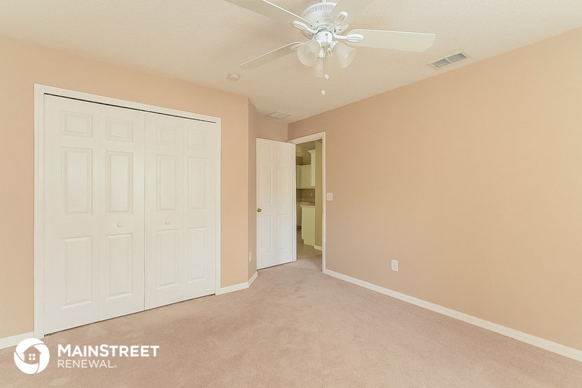a bedroom with a ceiling fan and a closet