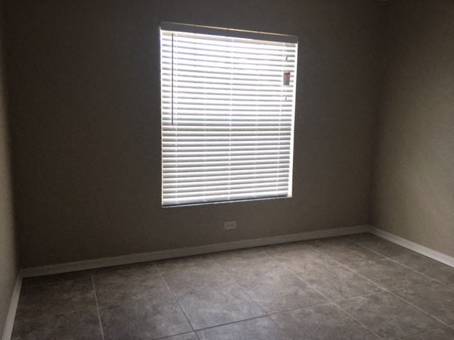 an empty room with a window and a tiled floor