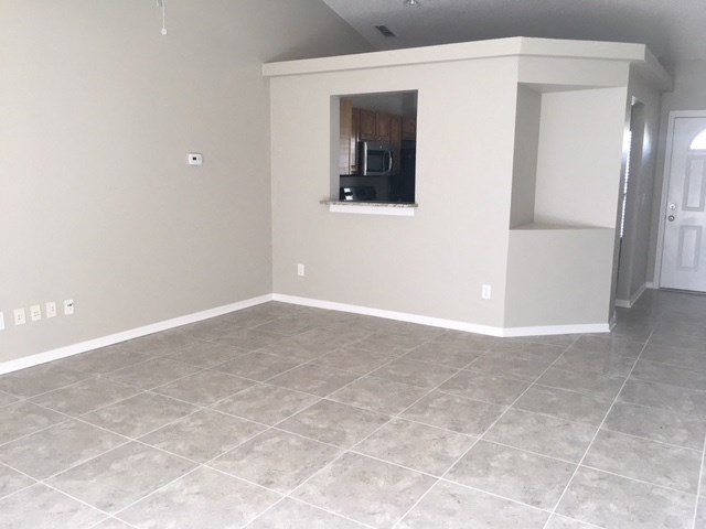 an empty living room with tile flooring and a window