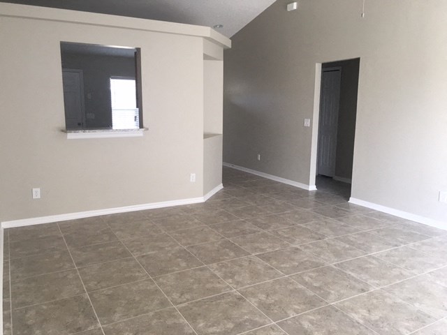 an empty living room with tile flooring and a window