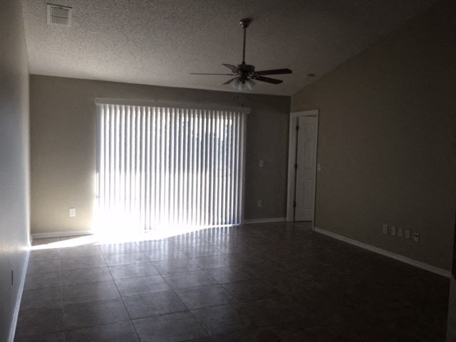 an empty living room with a ceiling fan and a window
