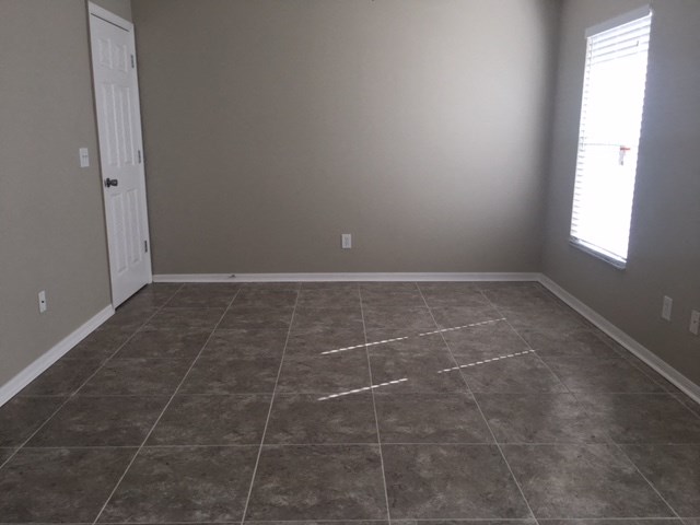 a large empty room with tile flooring and a door