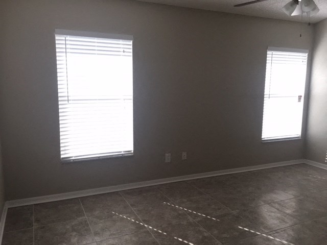 an empty room with two windows and a tiled floor