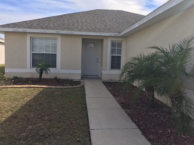 a sidewalk in front of a house with a blue door