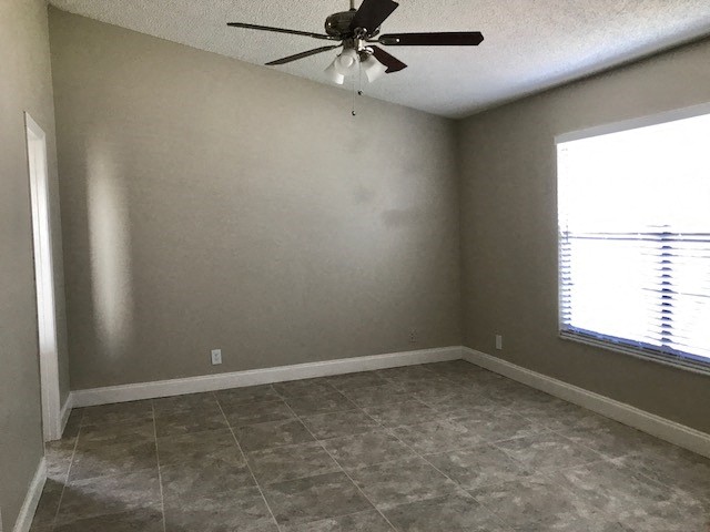 an empty room with a ceiling fan and a window