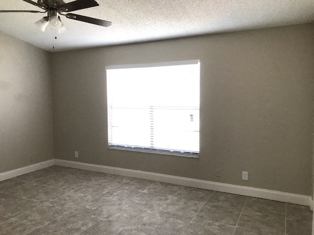 an empty room with a window and a ceiling fan