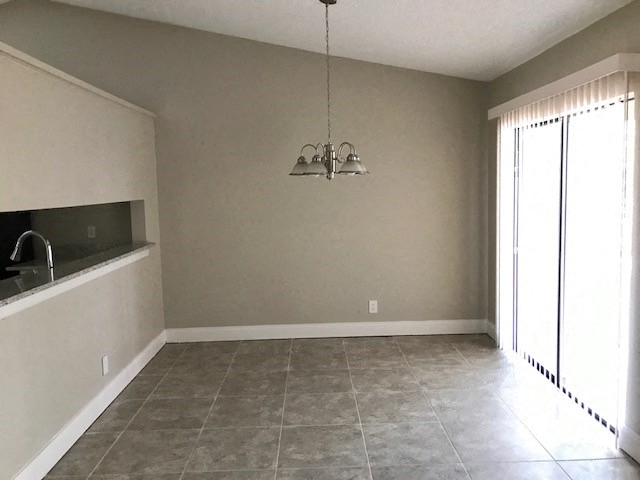 an empty living room with a chandelier and a window