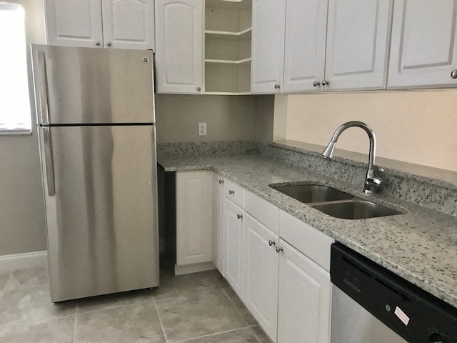 a kitchen with white cabinets and a sink and a refrigerator