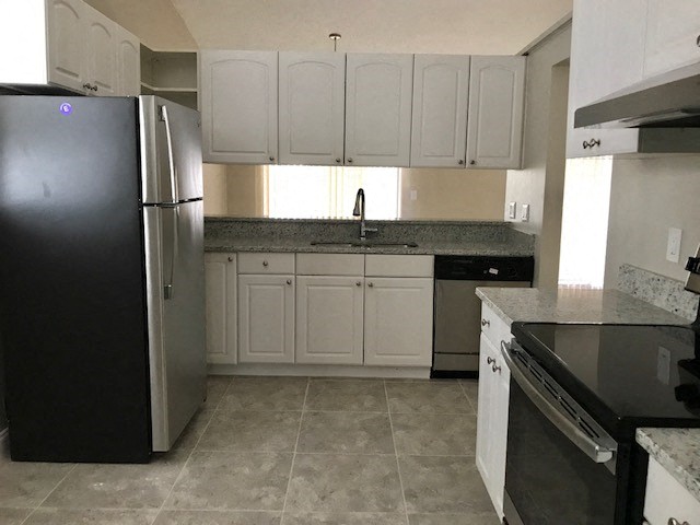 a kitchen with white cabinets and a black refrigerator