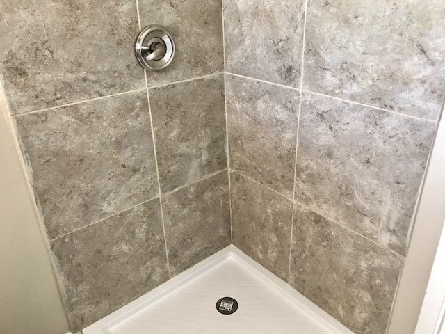 a bathroom with a shower and a tiled floor and walls