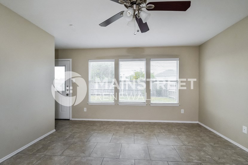an empty living room with a ceiling fan and a window