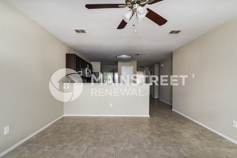 a renovated living room with a ceiling fan and tile floor