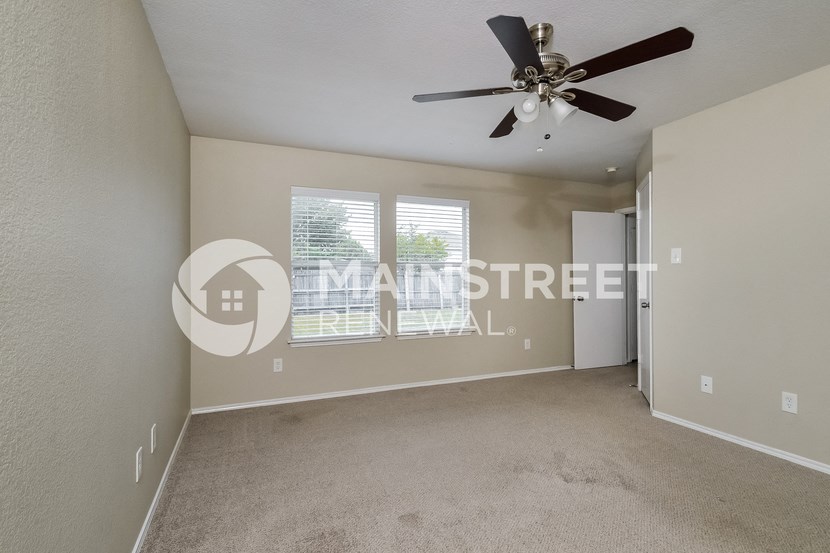 a living room with carpet and a ceiling fan