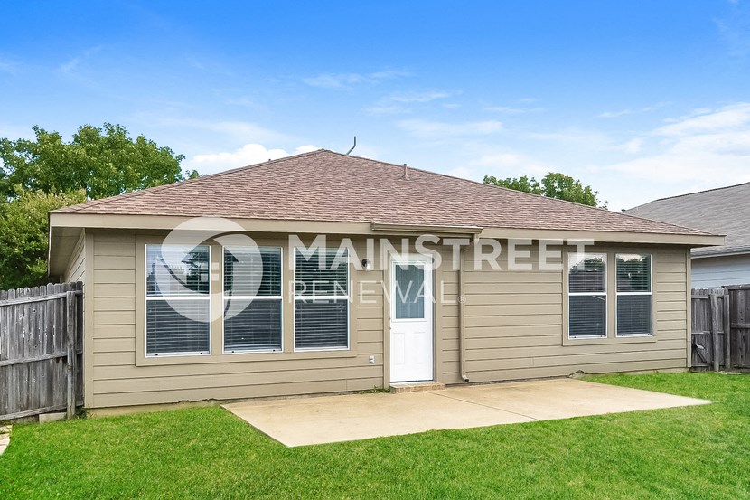 a small tan house with a white door and a lawn