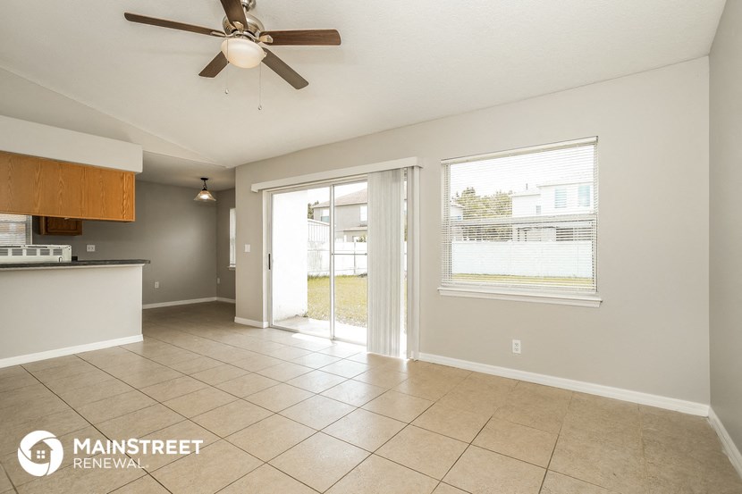an empty living room with a ceiling fan and a door to a patio