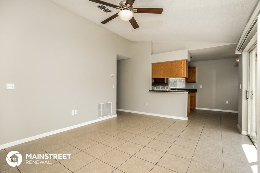 an empty living room and kitchen with a ceiling fan