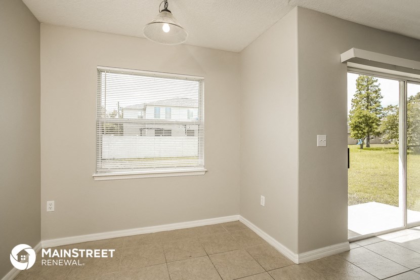 the living room of a home with a large window and a tile floor