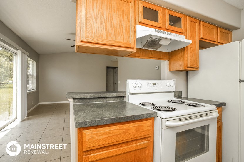 a kitchen with white appliances and wooden cabinets and a window