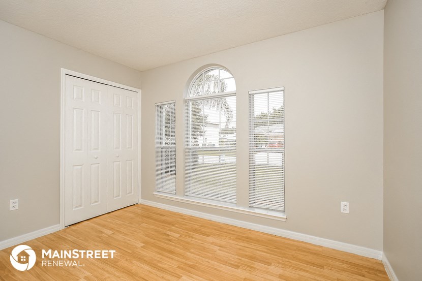 the living room of an apartment with wood floors and a large window