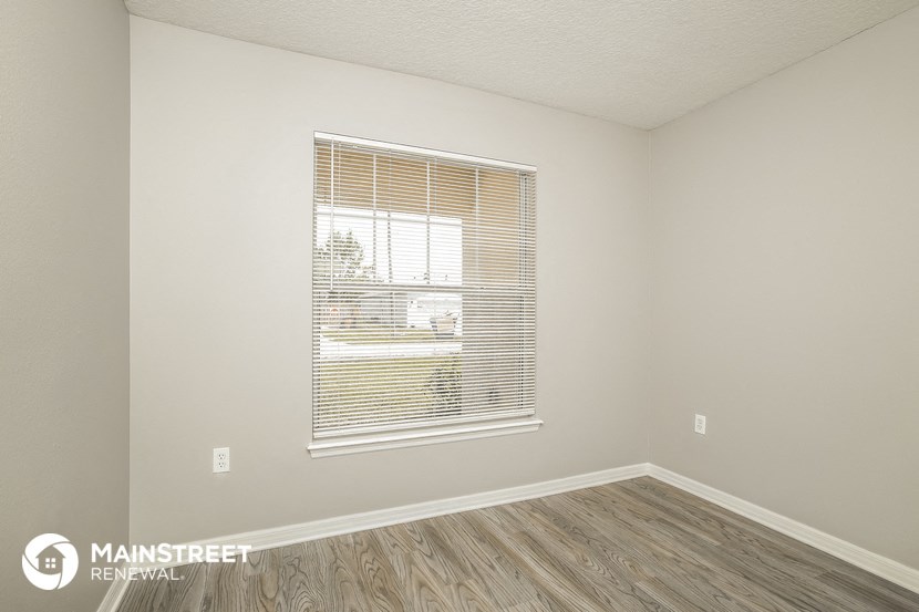 the spacious living room with a large window and wood flooring