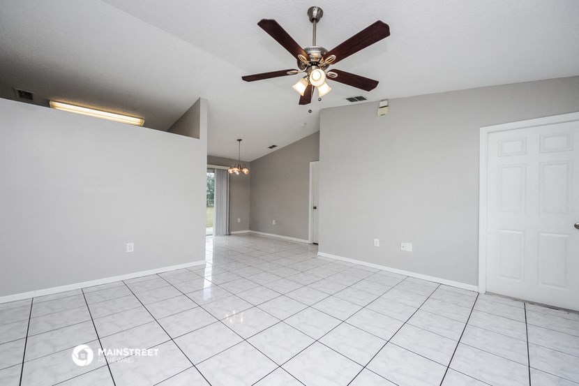 the spacious living room with tile flooring and a ceiling fan