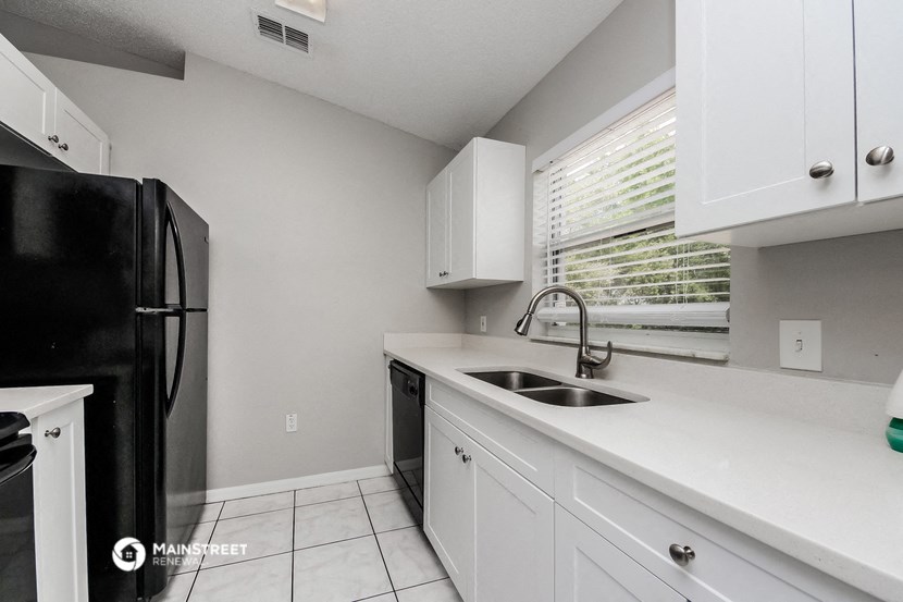 a kitchen with white cabinets and black appliances and a window