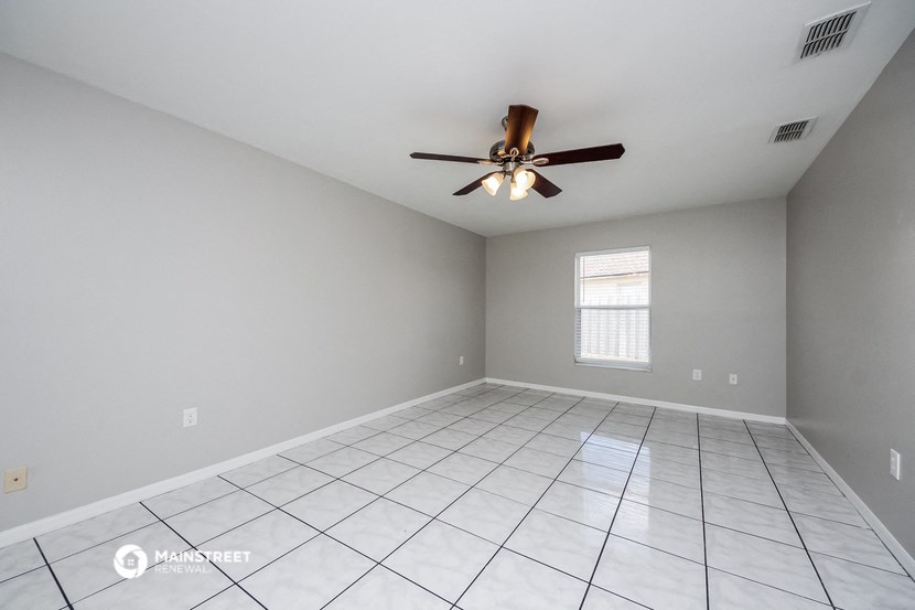 the spacious living room with tile flooring and a ceiling fan