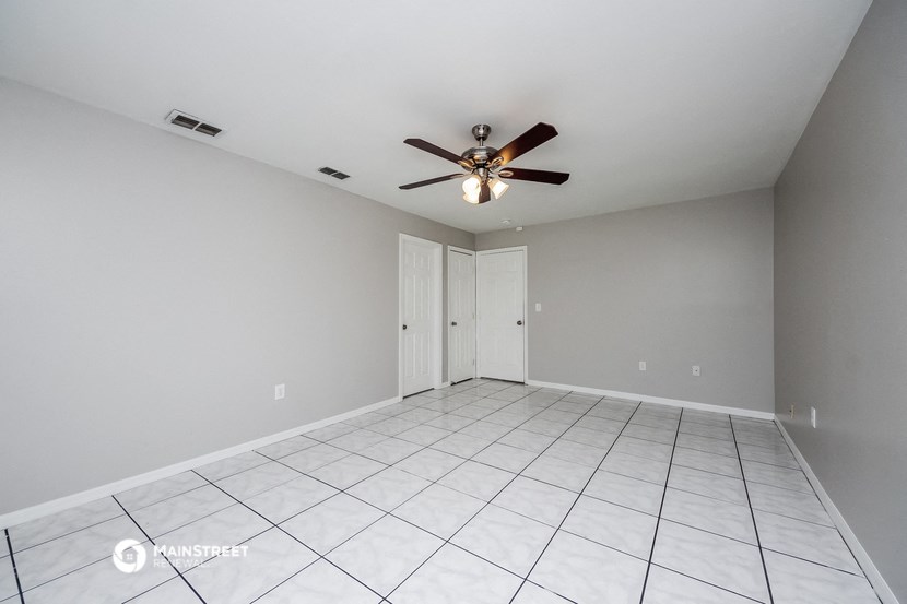 the spacious living room with tile flooring and a ceiling fan