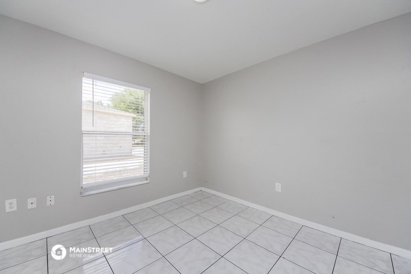 the living room of an empty house with a window and a tiled floor