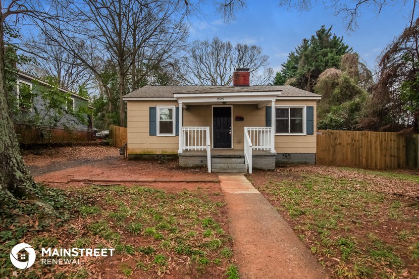 a small yellow house with a porch and a wooden fence