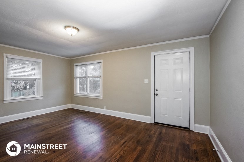 the master bedroom of a house with wood floors and a white door