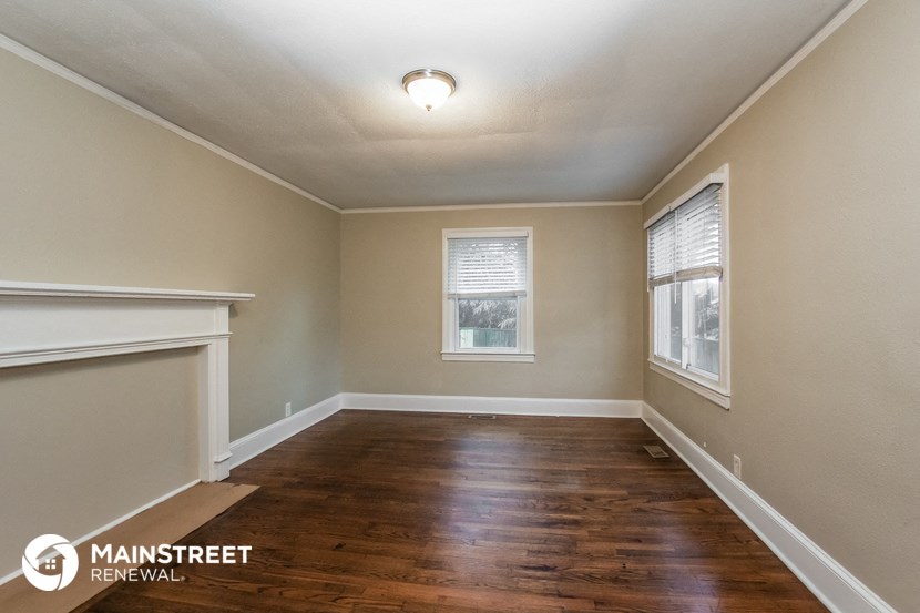 the living room of a house with a hardwood floor and a window