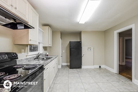a kitchen with white cabinets and a black refrigerator