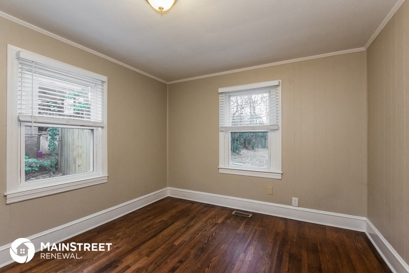 the living room of a house with wood floors and two windows