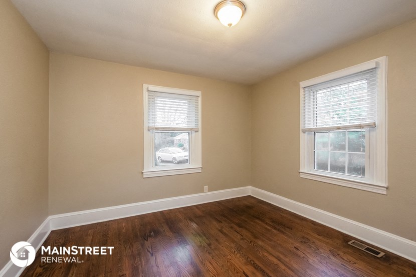 the living room of a home with a hardwood floor and two windows