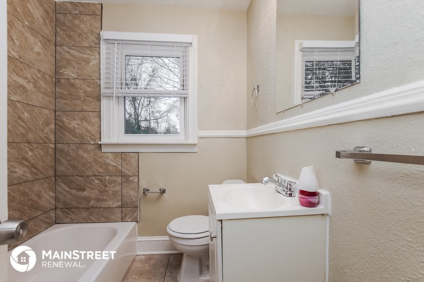 a bathroom with a toilet sink and mirror and a window