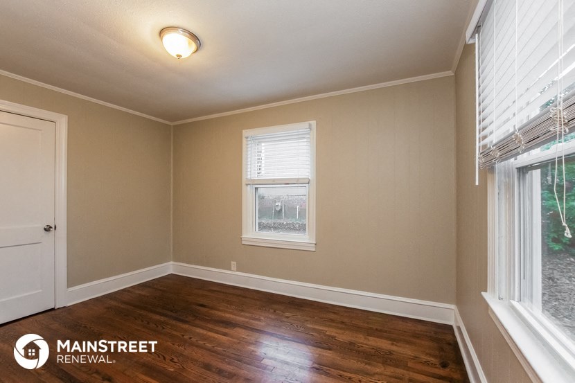 the living room of a home with wood floors and a window