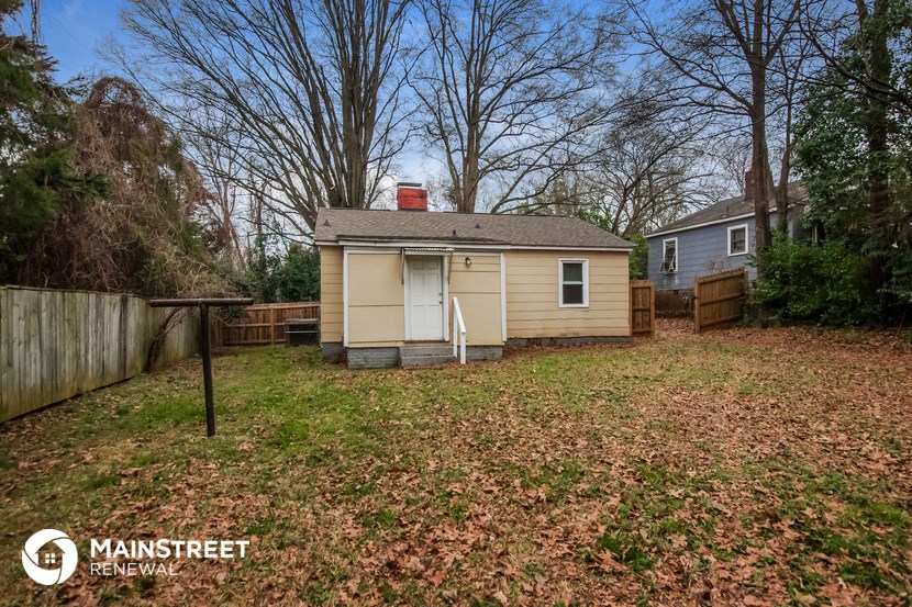 a small yellow house with a yard and a fence