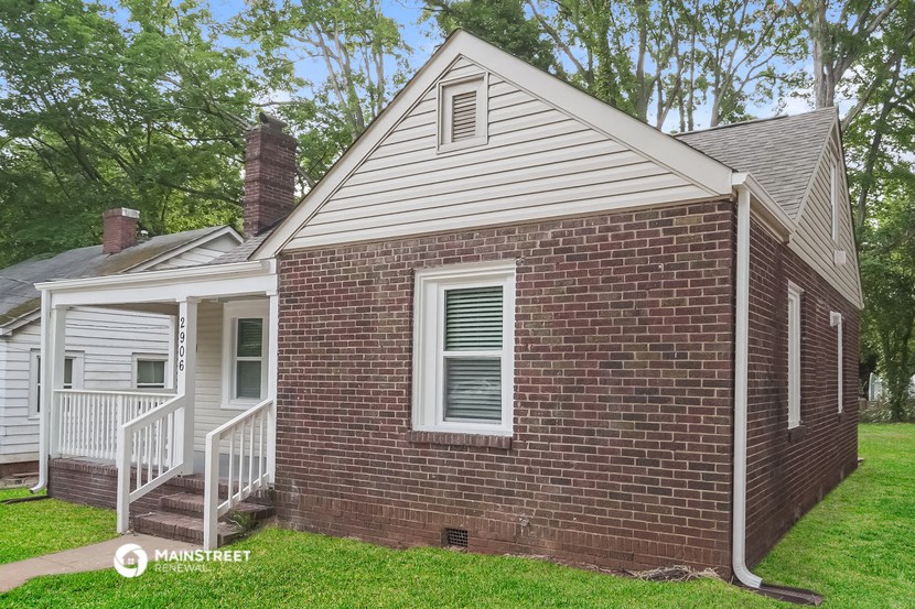 a small brick house with a porch and a white deck