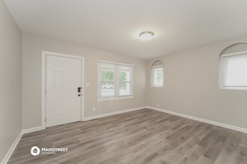 the spacious living room with wood flooring and a white door