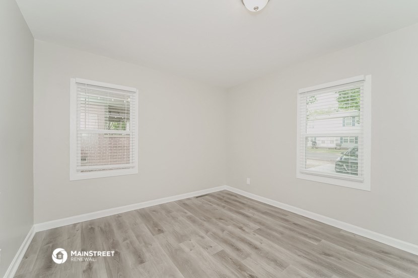 the spacious living room with wood flooring and two windows